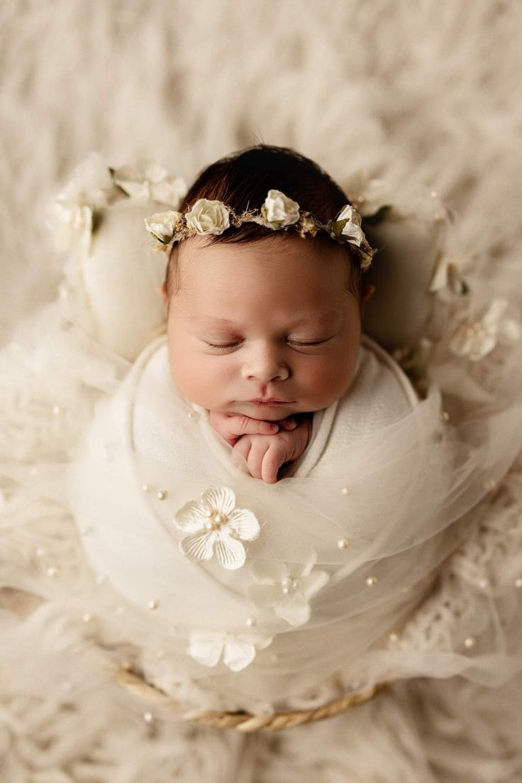 a newborn baby wearing a white flower headband