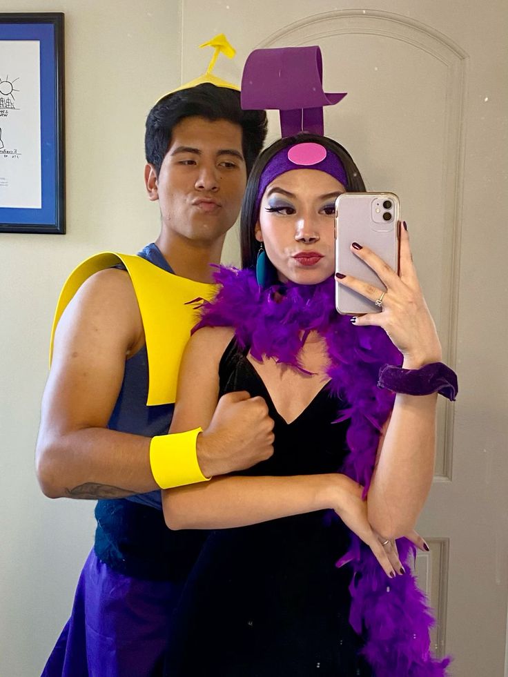 a man and woman in costume taking a selfie with a cell phone while standing next to each other