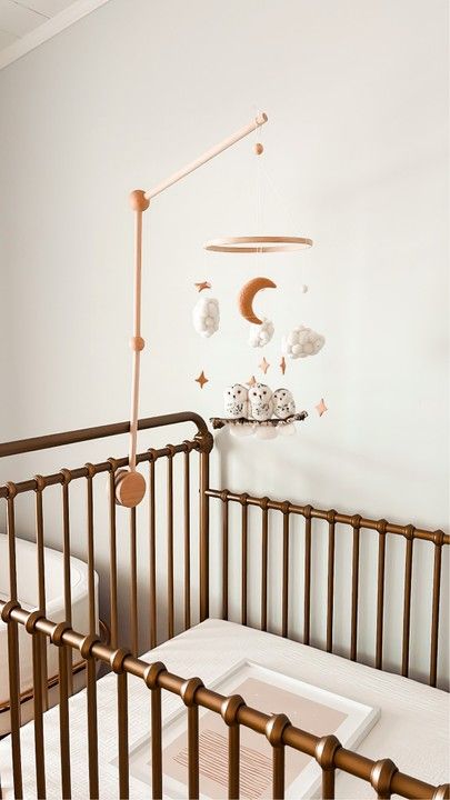 a baby crib with a mobile hanging from it's side in a white room