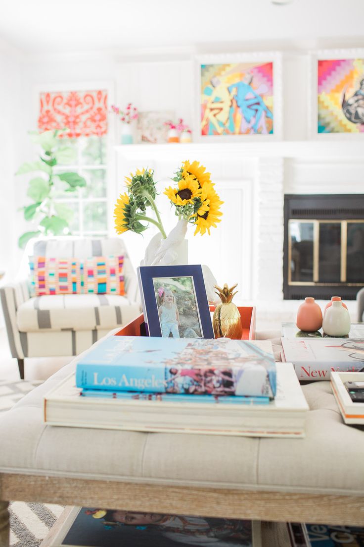 a living room with sunflowers in a vase and books on the coffee table