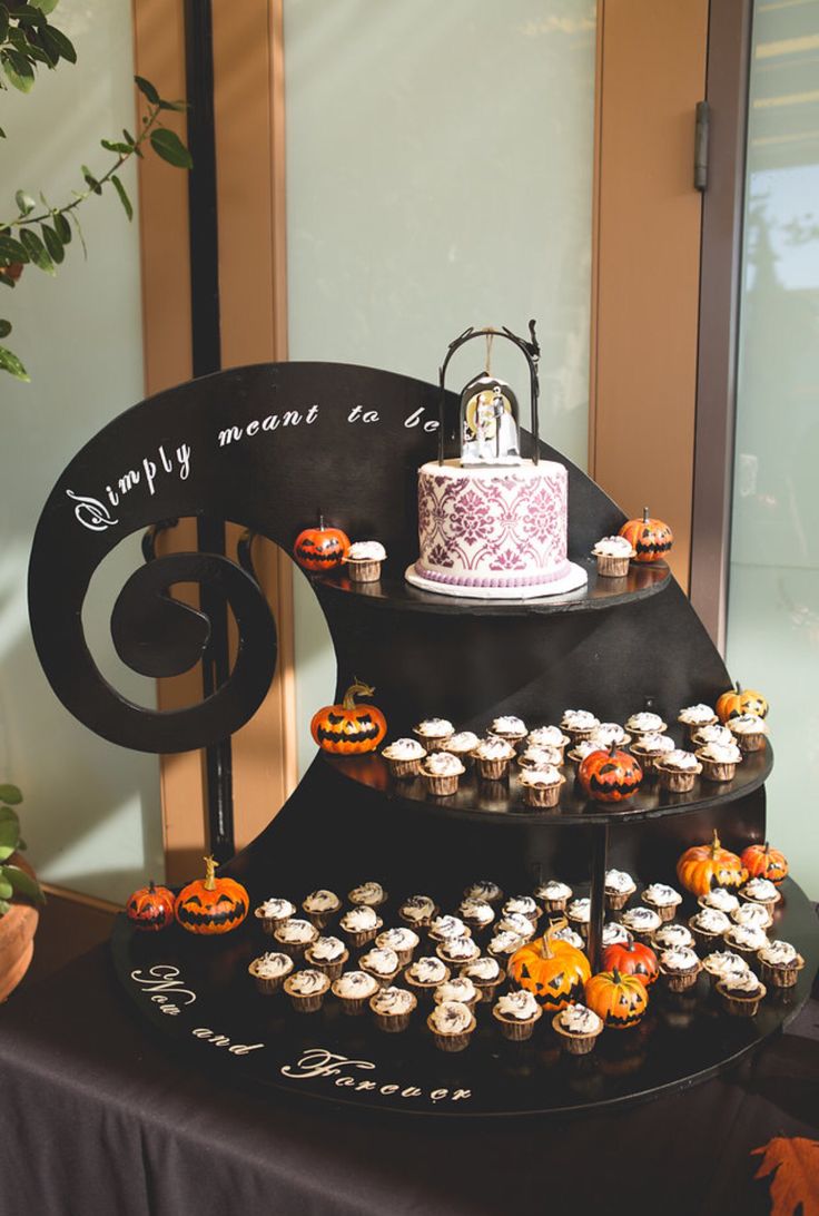 a three tiered cake and cupcake display on a table