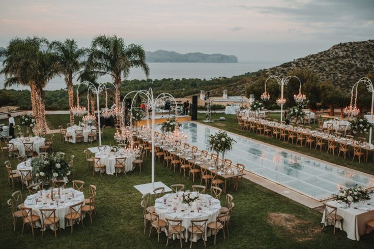 an outdoor venue with tables and chairs set up for a formal function by the water