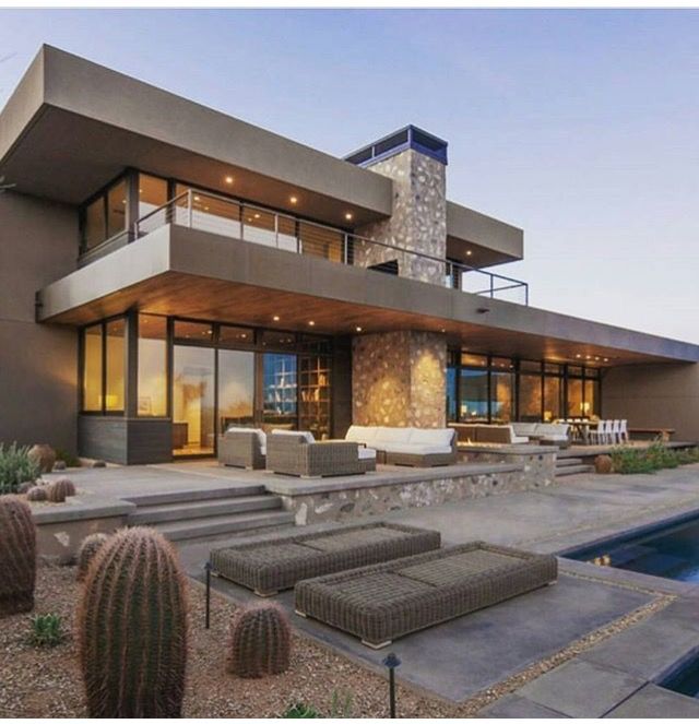 a large house with a pool in front of it and some cactus around the yard