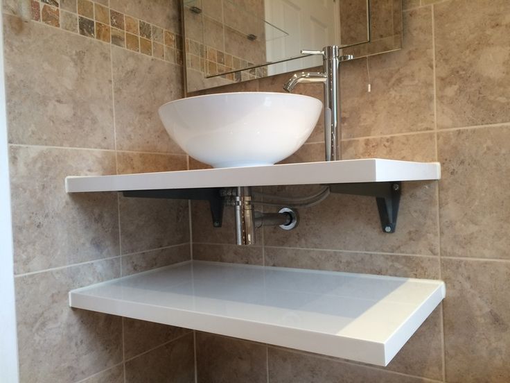 a bathroom sink sitting under a mirror next to a shelf with a bowl on it