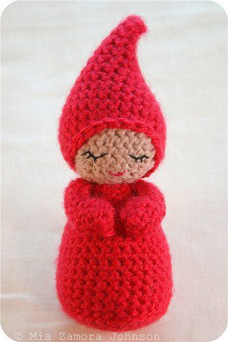 a crocheted doll with a red coat and hat on it's head