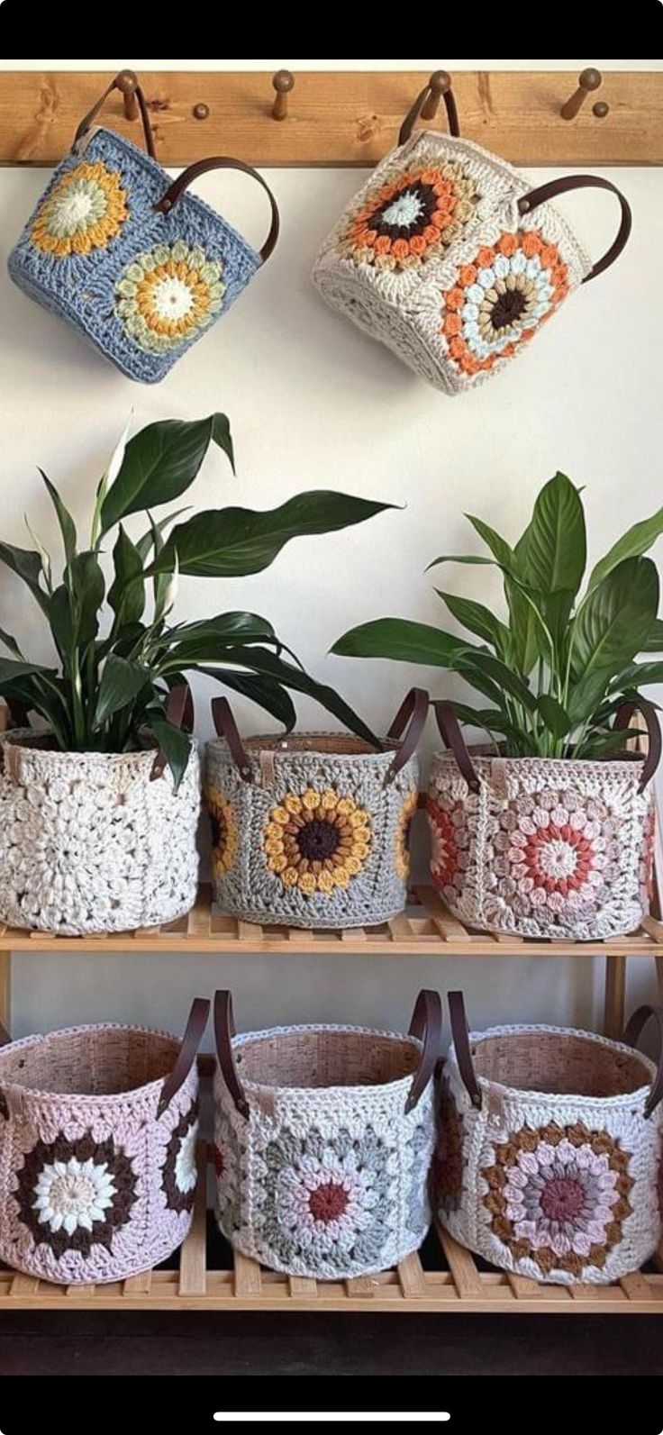 several crocheted baskets hanging on a wall with plants in them and one has a potted plant next to it