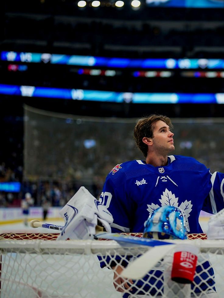 a hockey player sitting in the goalie's net with his hands on his knees