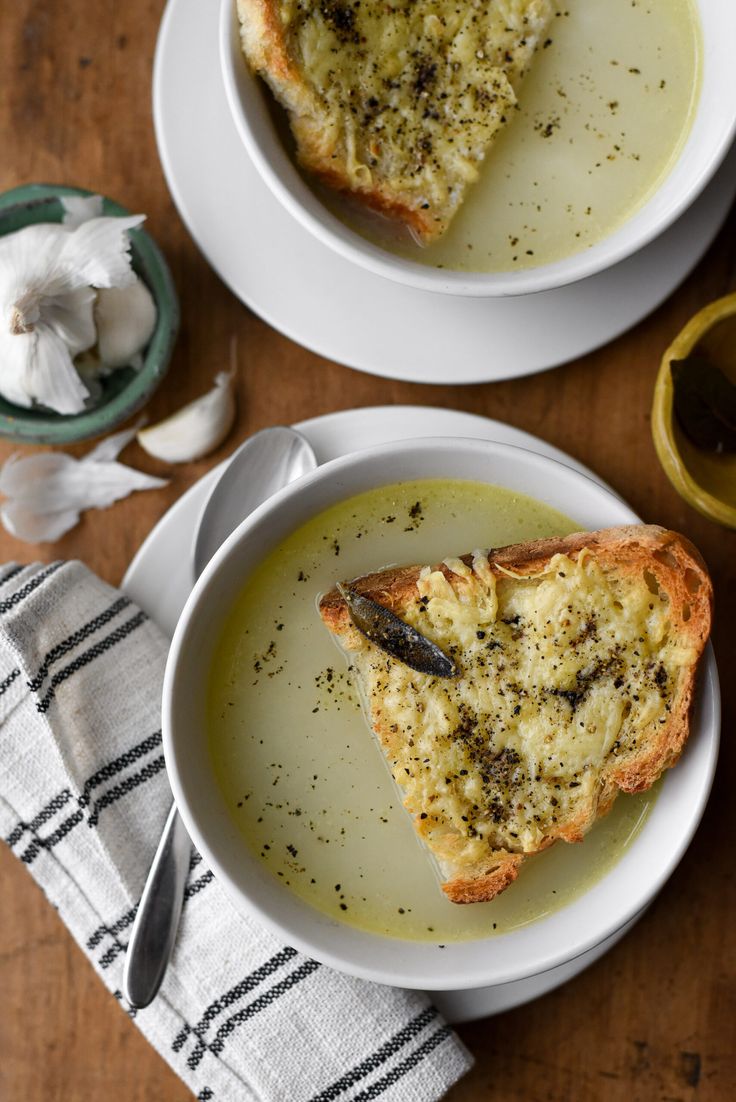 two white plates topped with soup and bread