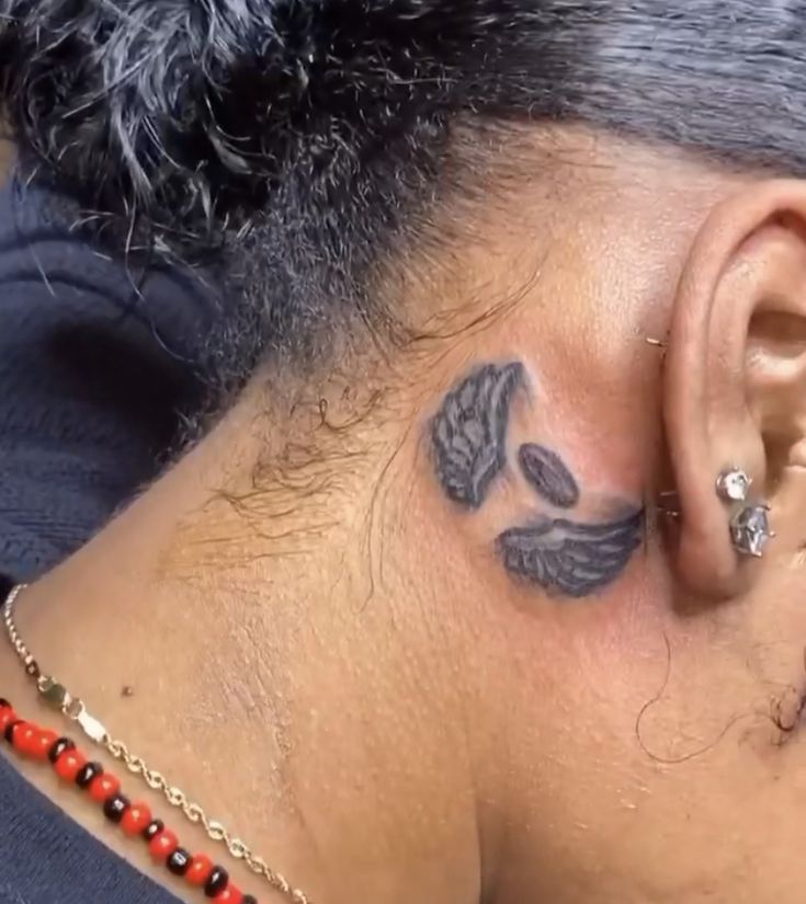 an ear tattoo with feathers on it