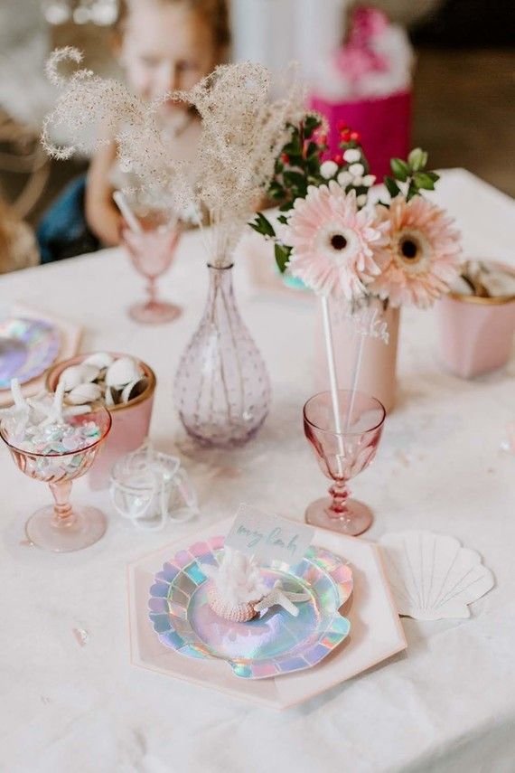 a table topped with pink vases filled with flowers and plates covered in confetti