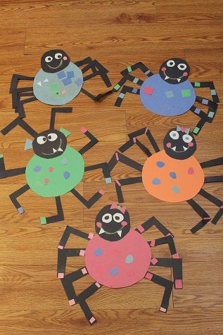 paper cut out of the shape of a spider with eyes and legs, sitting on a wooden floor