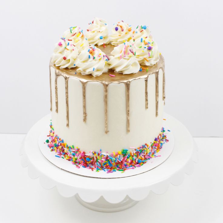 a cake with white frosting and sprinkles on top sitting on a plate