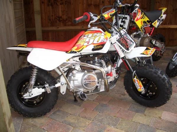 a dirt bike parked in front of a wooden wall with other bikes behind it on display