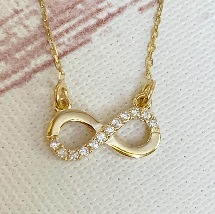 "This Infinity necklace is 14K Solid GOLD ( not filled or plated) furnished with cubic zirconia diamonds. All our gold pieces are suitable for all kinds of clothing and add a great sparkle to your wardrobe. This beautiful, timeless necklace can be wear alone or layered with other items in my shop. Delicate and chic. This gorgeous gold necklace could make a perfect gift for your loved one. ♥ - WEIGHT:1.57  gr - LENGHT: 16\" - All OUR ITEMS WILL COME IN GIFT BOXES HOW TO CARE FOR YOUR JEWELRY: + U Gold Infinity Jewelry Gift For Her, Gold Infinity Jewelry As A Gift For Her, Dainty Infinity Necklace As Gift For Her, Gold Infinity-shaped Jewelry Gift For Her, Dainty Yellow Gold Infinity Necklace, Gold Plated Infinity Jewelry As A Gift, Gold Plated Infinity Jewelry Gift, Dainty Infinity-shaped Gold Jewelry, Gold-plated Infinity Jewelry Gift