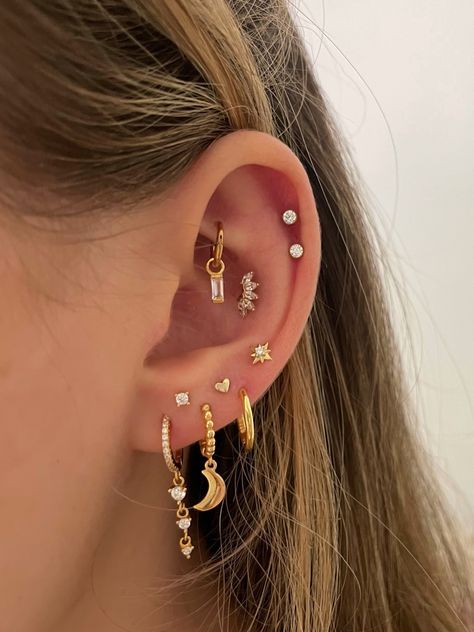 a woman wearing three different ear piercings with stars and moon designs on the side