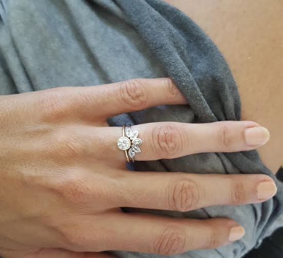 a woman's hand with a gold ring on it and a flower in the middle