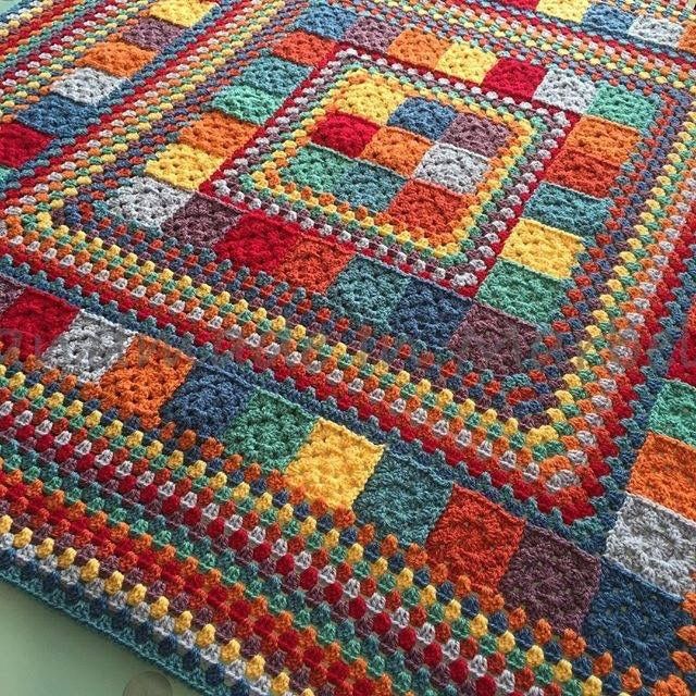 a multicolored crocheted afghan with squares on it's sides and bottom