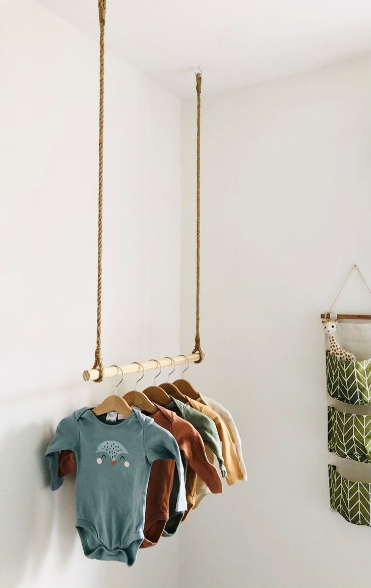 a baby's bodysuit hanging from a rope in front of a white wall