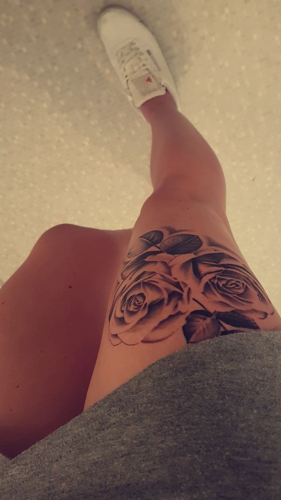 a woman's leg with a rose tattoo on her left side, and white shoes in the background