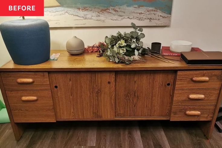 a wooden table topped with lots of drawers next to a vase filled with flowers and plants