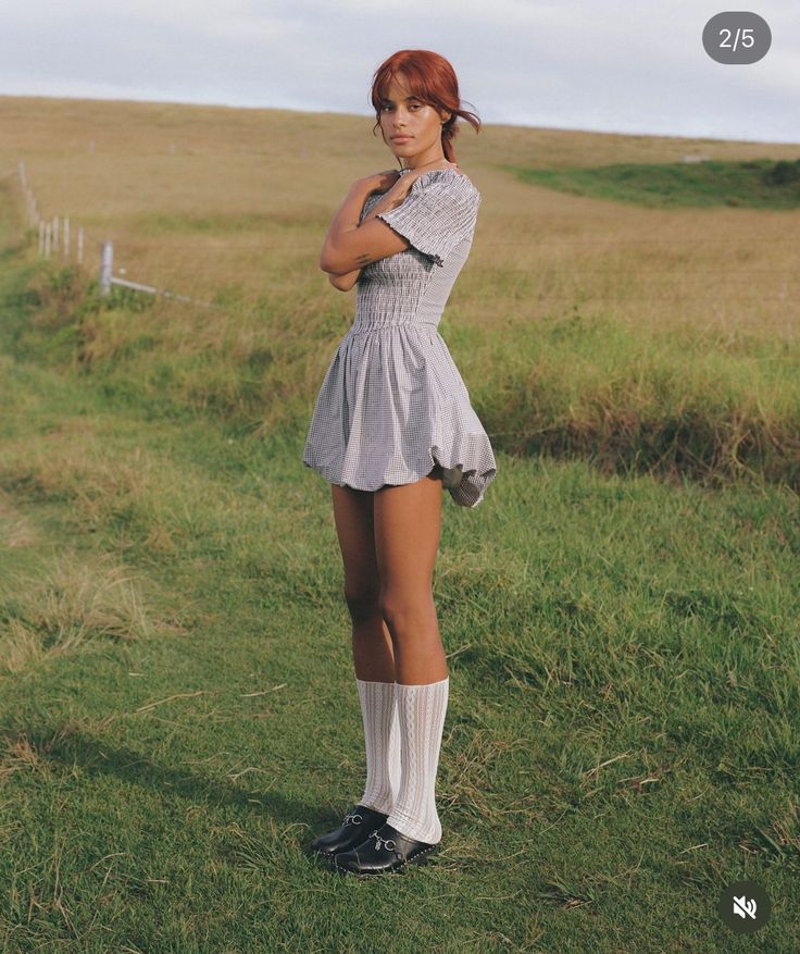 a woman standing on top of a lush green field next to a grass covered field