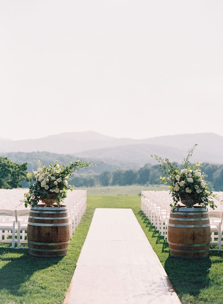 an outdoor ceremony setup with wooden barrels and flowers