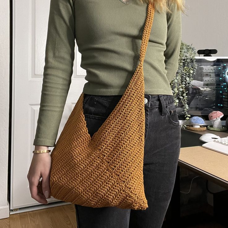 a woman standing in front of a white door holding a brown knitted handbag