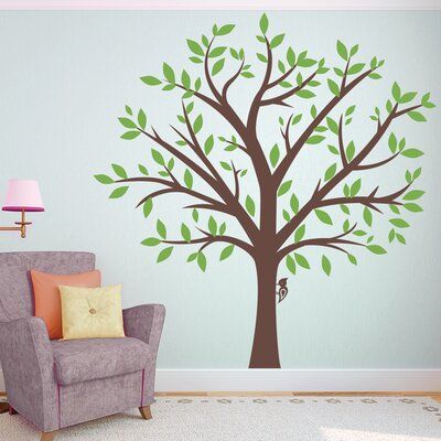 a living room with a chair and tree wall decal