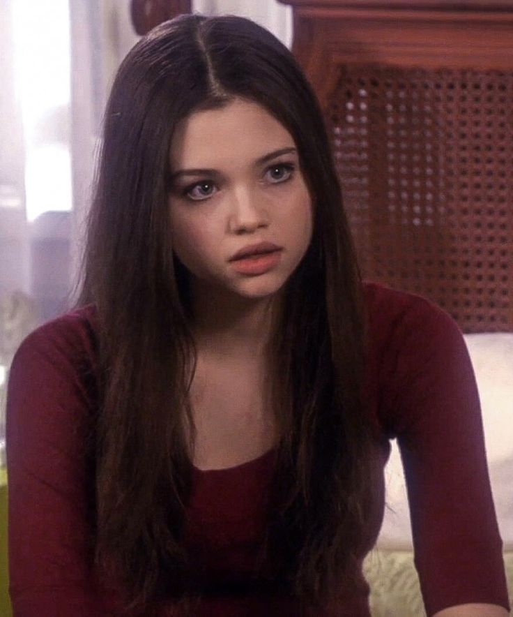 a woman with long hair sitting on a bed