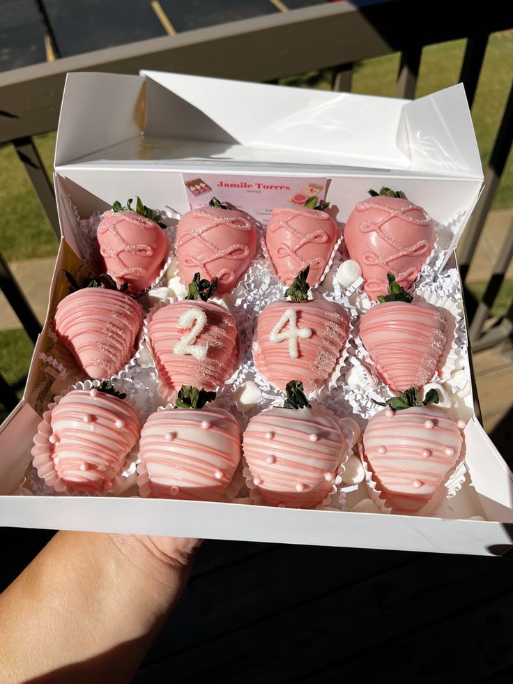 a box filled with pink frosted chocolate covered strawberries