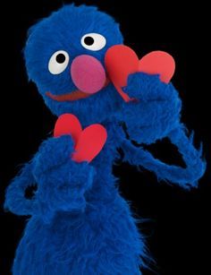 a blue stuffed animal holding two red hearts