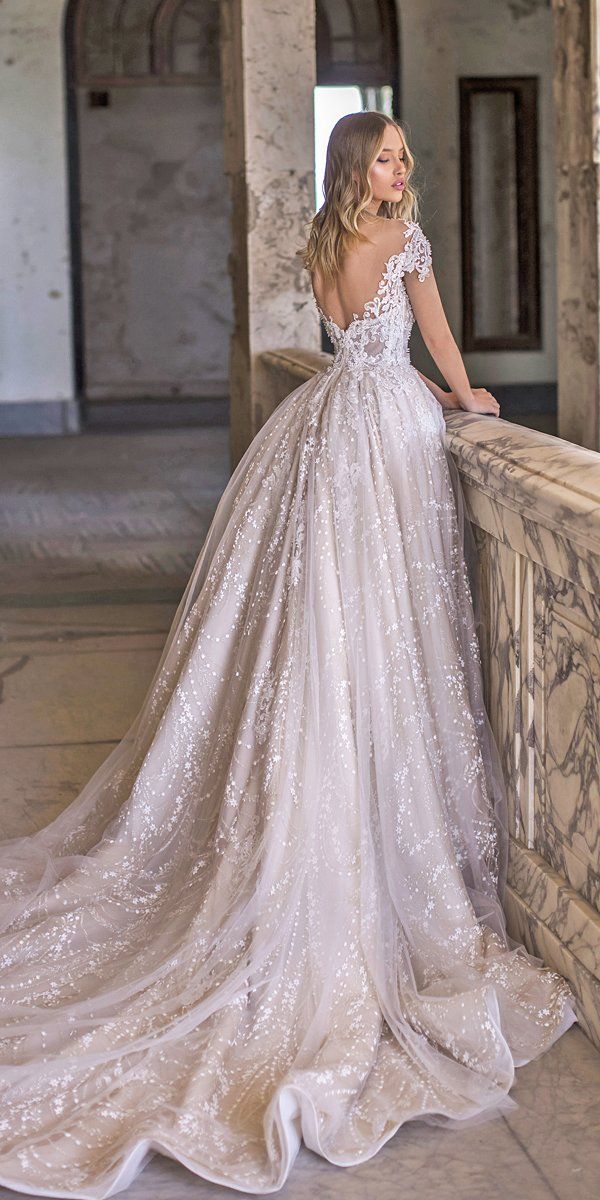 a woman in a wedding dress leaning on a wall with her back to the camera