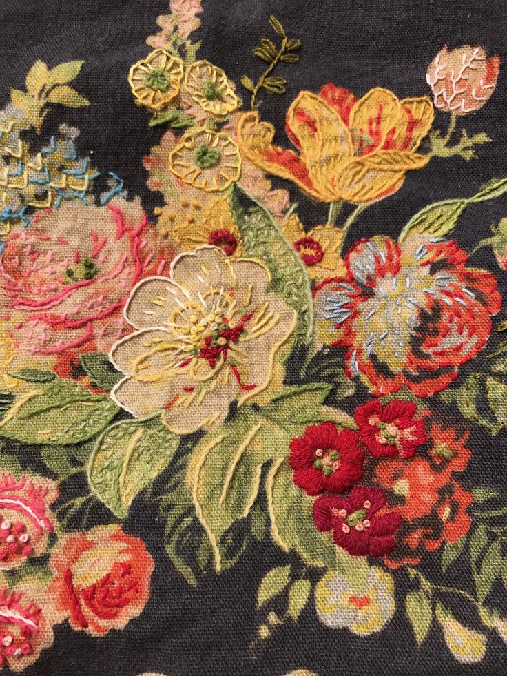 an embroidered piece of cloth with flowers and leaves on black background, close - up