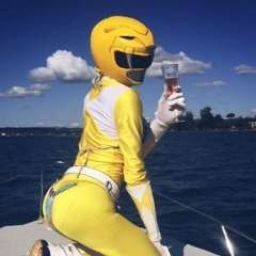 a person dressed in yellow is sitting on a boat and holding a drink with both hands