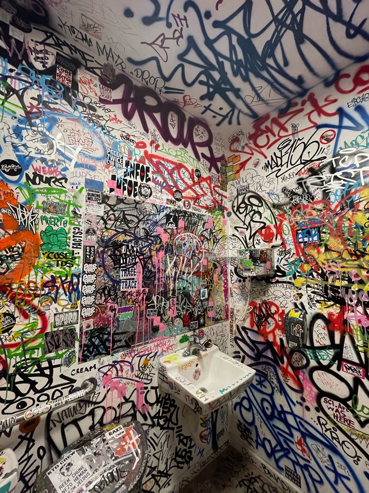 a bathroom with graffiti all over the walls and on the wall is a white sink