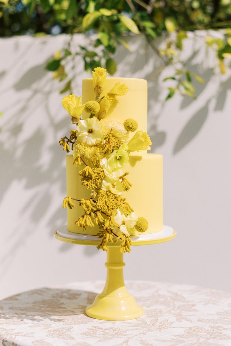 a yellow wedding cake with flowers on top