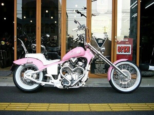 a pink motorcycle parked in front of a building