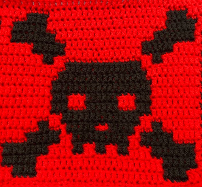 a red and black crocheted bag with a skull on the front, cross - stitched into it