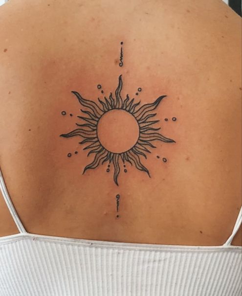 the back of a woman's shoulder with a sun tattoo on it