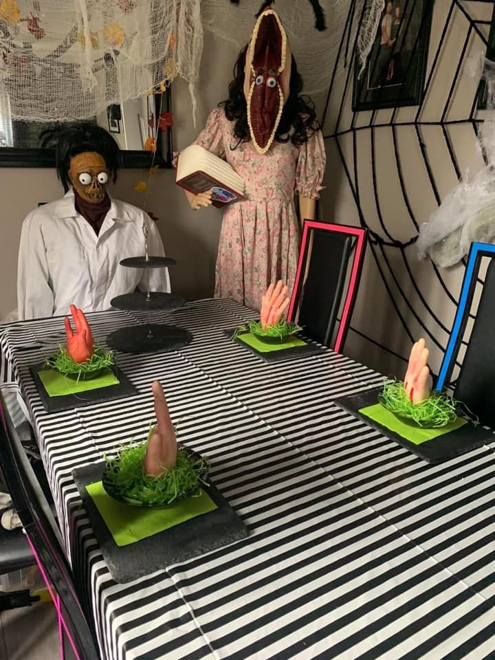 two mannequins dressed in costumes sit at a table with green plates on it