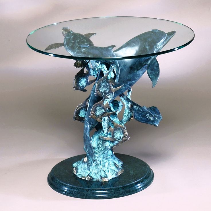 a glass table topped with a metal dolphin sculpture