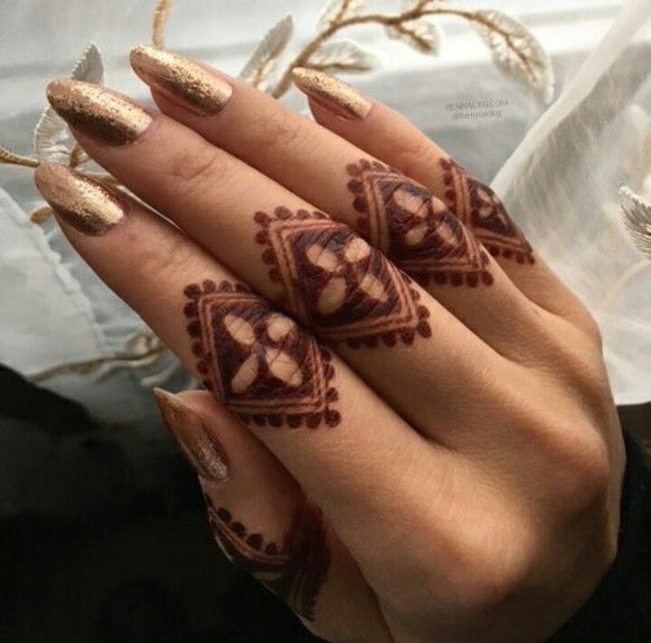 a woman's hand with hennap and gold nail polishes on it