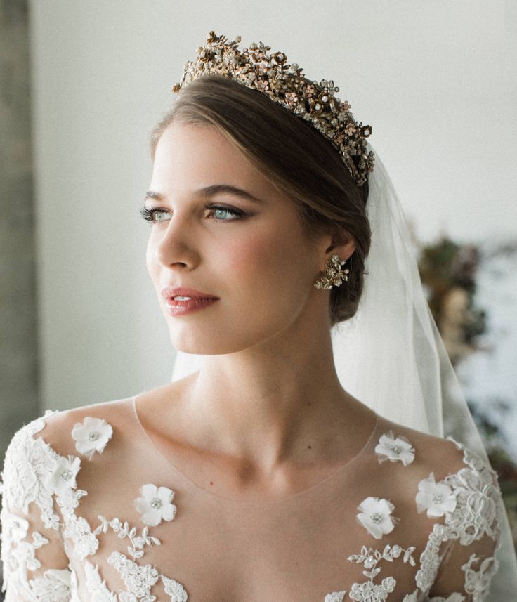 a woman in a wedding dress wearing a tiara with flowers and pearls on it