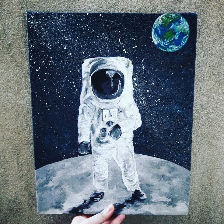 a painting of an astronaut on the moon is being held up by someone's hand