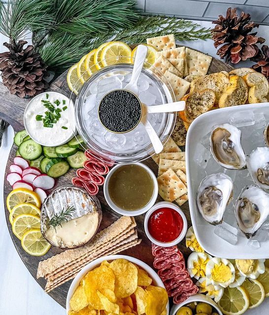 a platter filled with oysters, crackers, cucumbers and other foods