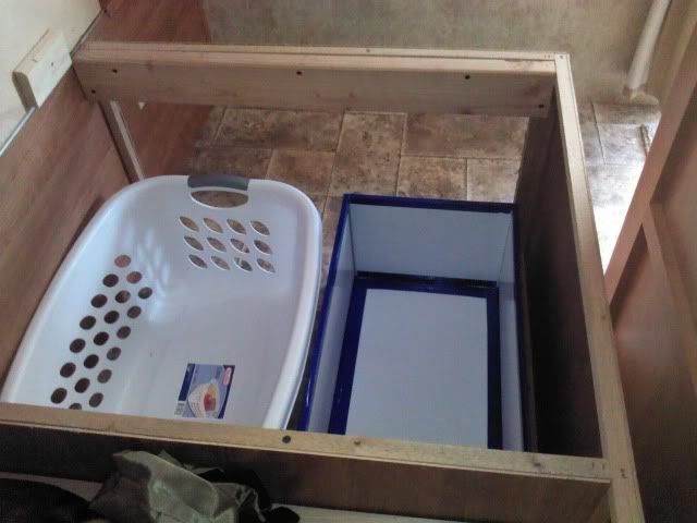 two laundry baskets sitting inside of a wooden box