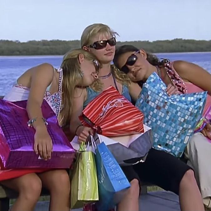 three women sitting on a bench with shopping bags in their hands and one woman holding her belly