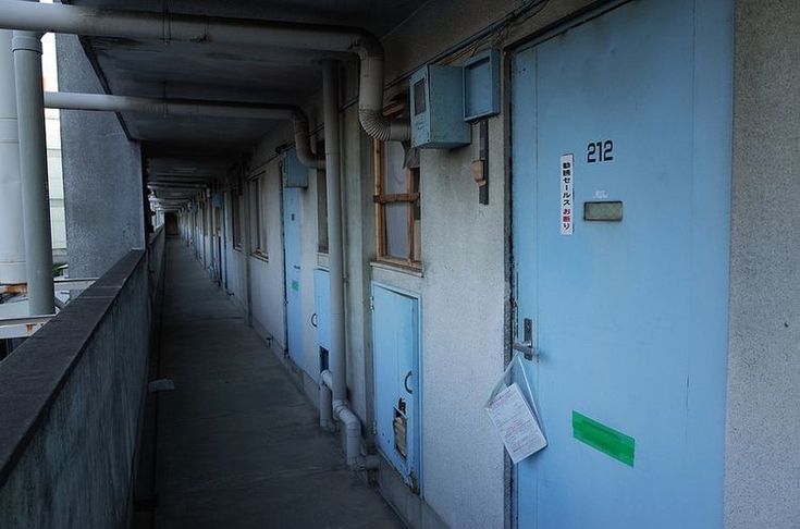 an empty hallway with blue doors and signs on the door, in front of a building