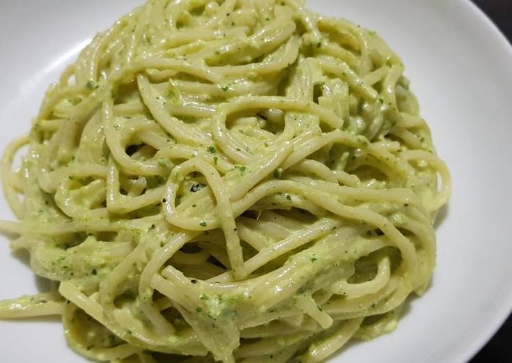 a white plate topped with pasta covered in pesto