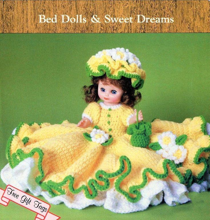 a crocheted doll is wearing a yellow dress and hat with flowers on it